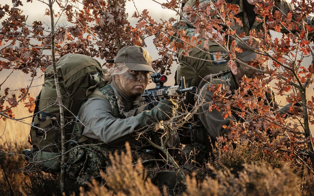 Jonge vrouw in militair uniform richt haar geweer.