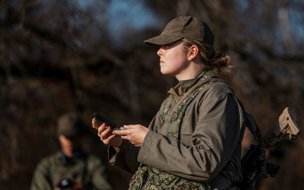 Een jonge vrouw in militair uniform kijkt geconcentreerd naar links. In haar hand houdt ze navigatie.