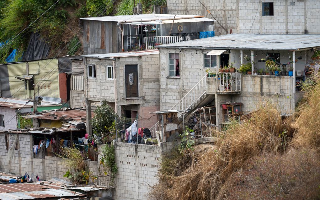 Povere huizen, sommige van enkel golfplaten, kriskras door elkaar, tegen een heuvel aan.