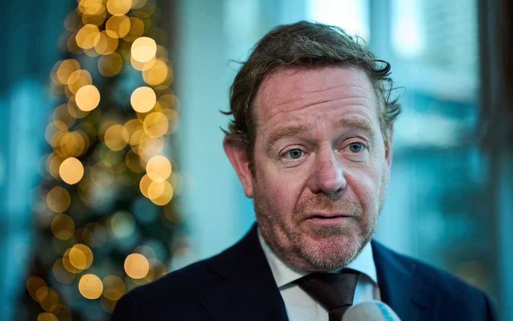 pasfoto van licht bebaarde man van middelbare leeftijd met colbert en stropdas.