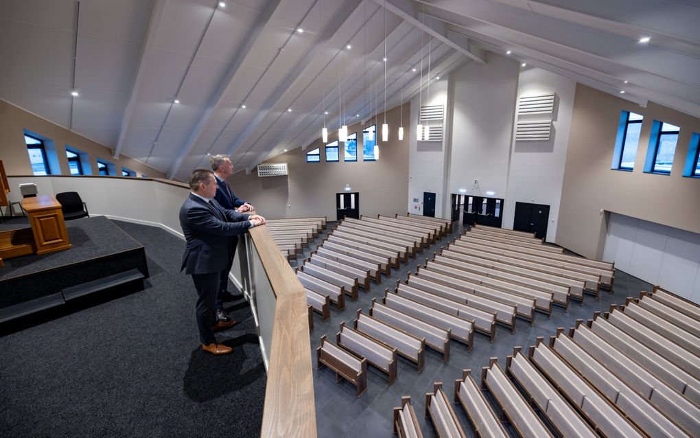 Twee mannen kijken vanaf de galerij naar de kerkruimte beneden hen.