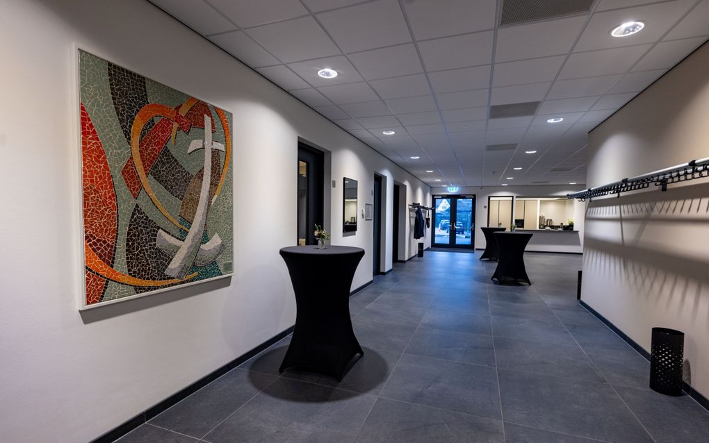 Een ruime gang, met statafels. Aan de wanden links kunstwerken.
