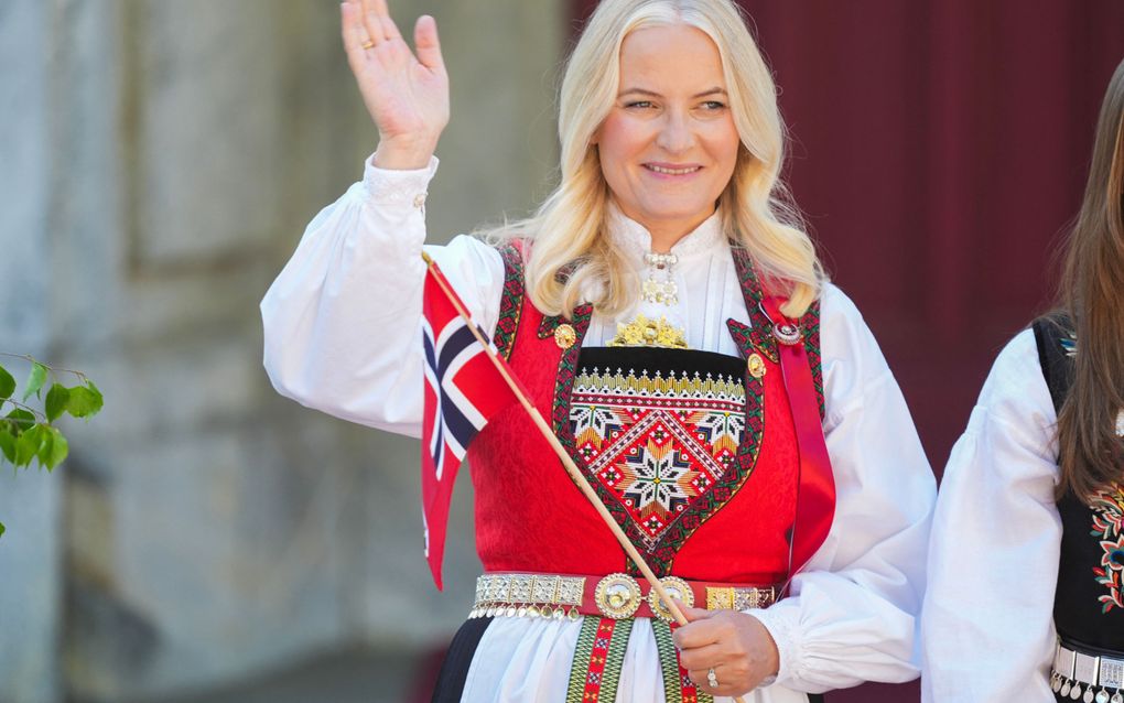 Blonde vrouw met Noorse vlag en klederdracht.