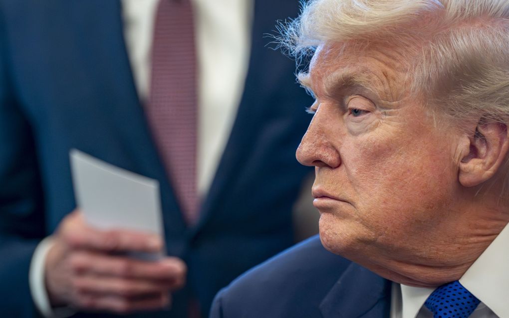 Blonde man in blauw pak kijkt opzij. 