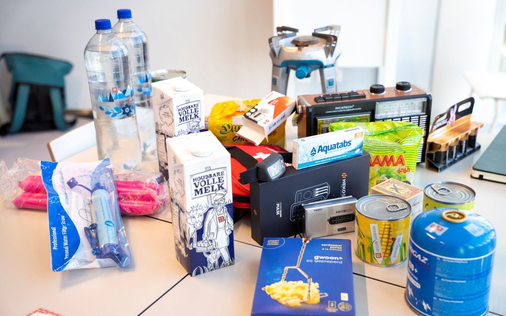 Etenswaren en spullen als een radio en een gasbrander staan op bij elkaar geschoven tafels.