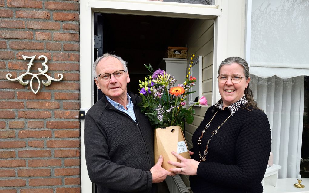 Annie Verhoeven-van Horssen geeft haar schoonvader Wim Verhoeven een bloemetje. „Hij is elke zaterdag bij ons kerkgebouw te vinden om alles in orde te maken voor de diensten de volgende dag.” beeld Erald van der Aa