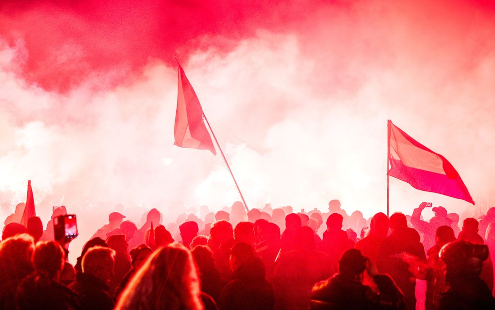Silhouetten van demonstranten en veel rook en rood licht. 