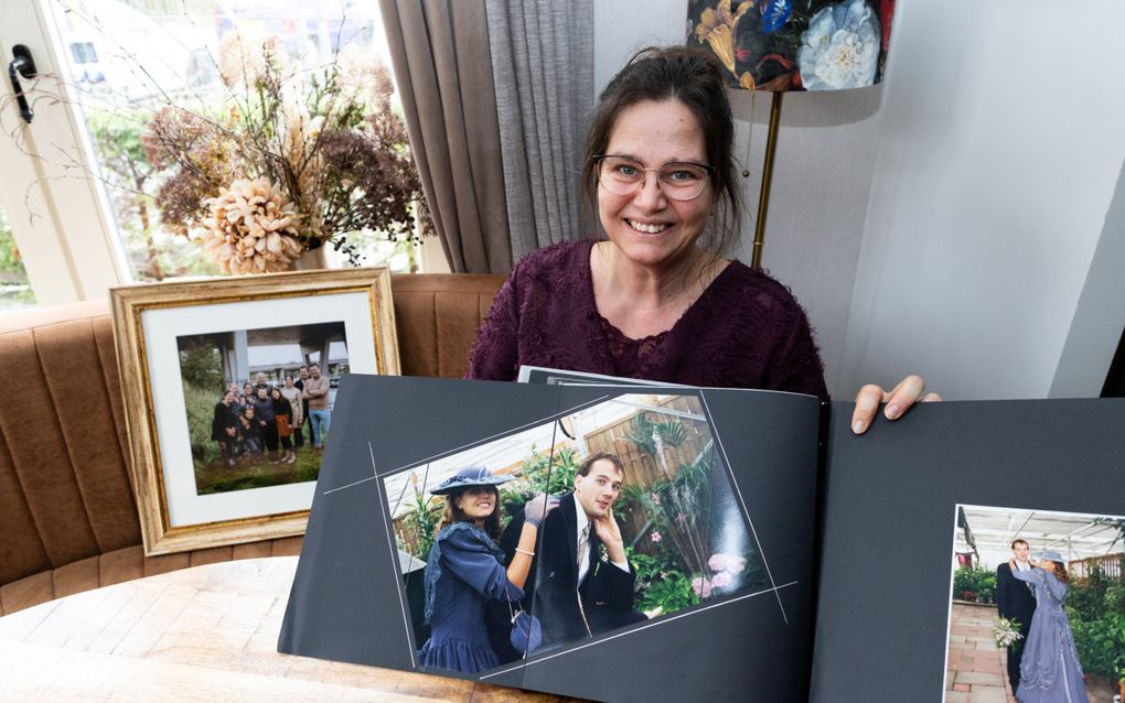 Durvina Slingerland met familiefoto’ s. Ze heeft haar trouwalbum vast. 