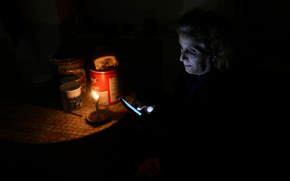 Een vrouw kijkt op een scherm bij een kaars. 