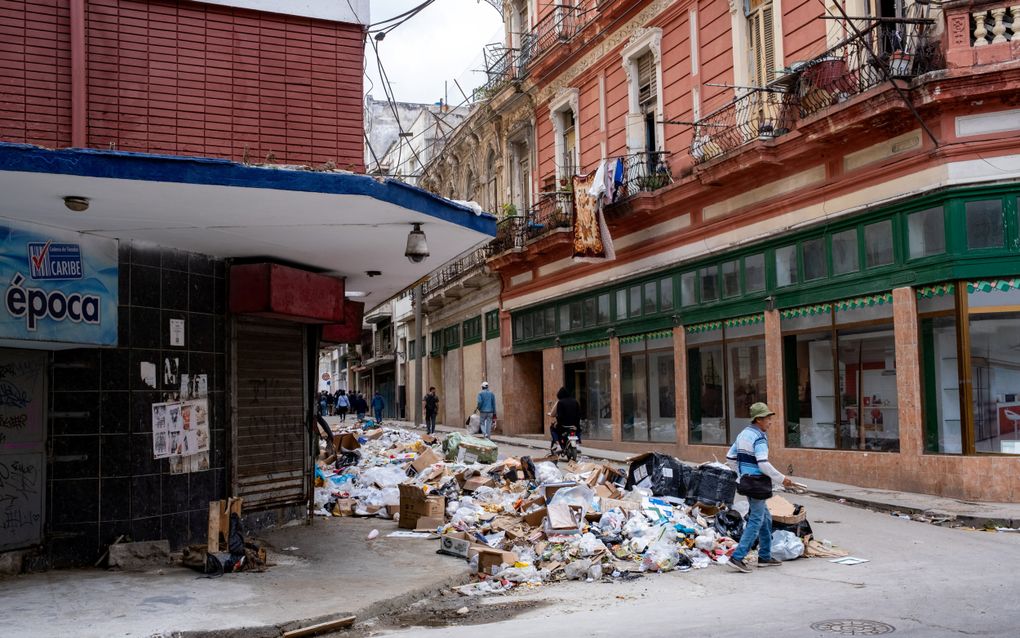 Plastic zakken en kartonnen dozen tussen roodgekleurde huizen. 