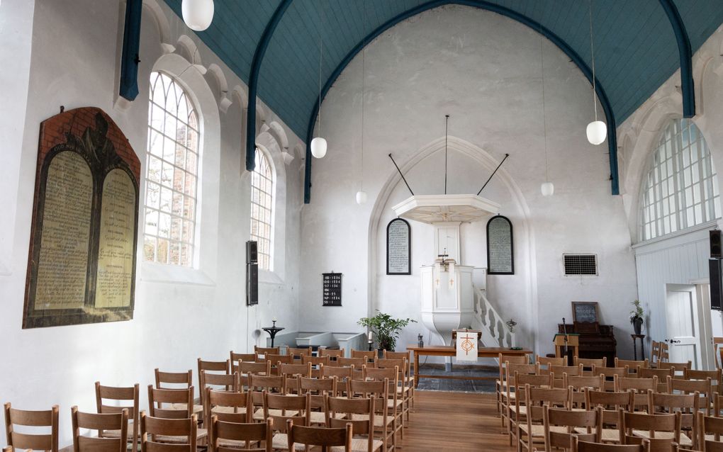 Houten stoelen voor witte kansel in kerk.