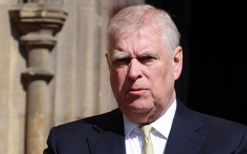 Een man met grijs haar in pak knijpt zijn ogen bijna dicht tegen de zon. 