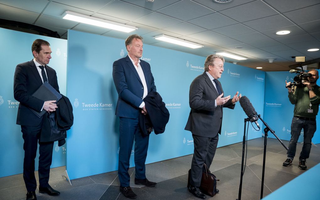 Drie mannen in pak voor lichtblauw decor