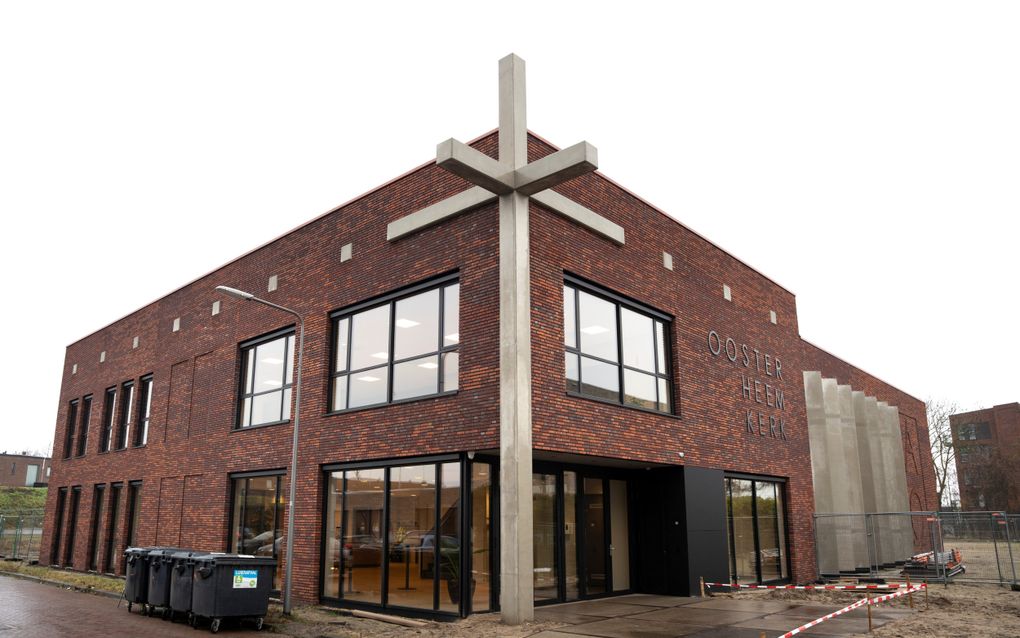 Gloednieuw kerkgebouw, met een groot betonnen kruis ervoor.