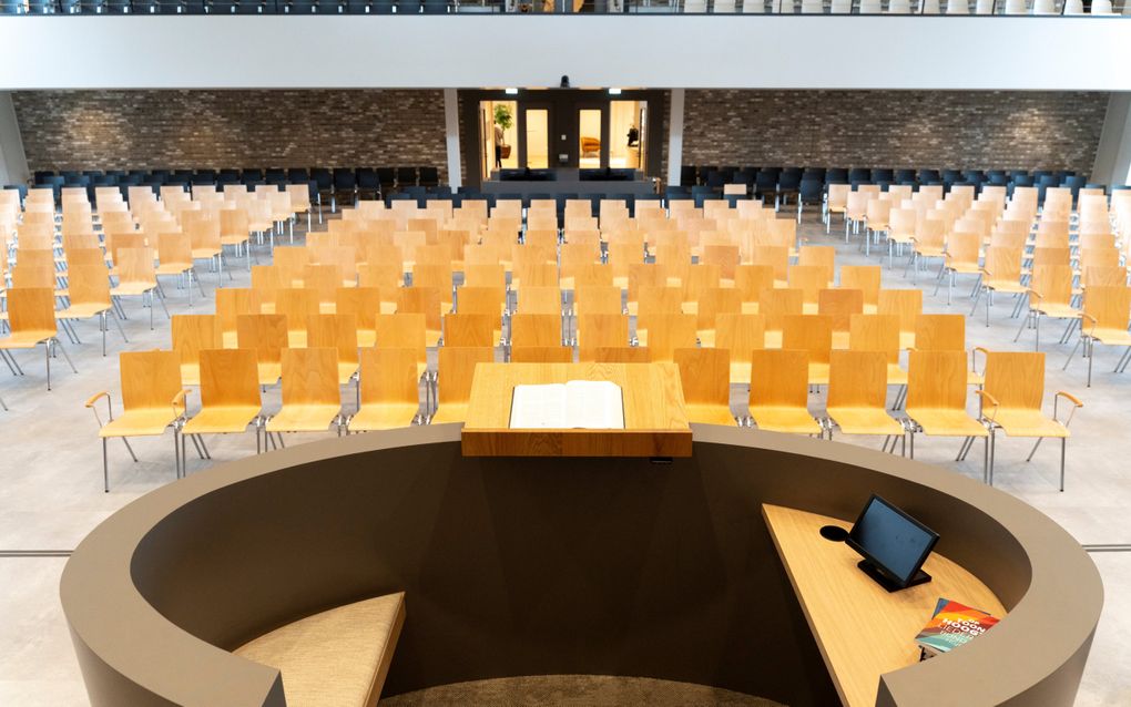 Blik in de kerkzaal, met houten stoelen.