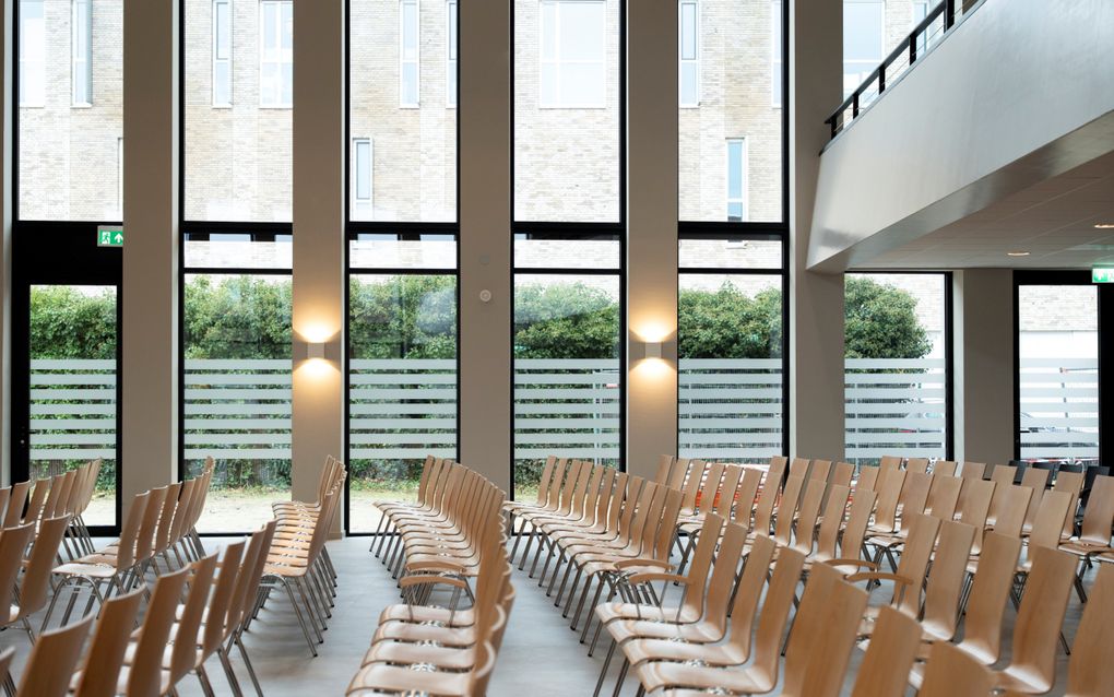 Rijen stoelen, hoge ramen.