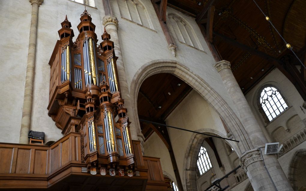 In een grote kerk hangt een pijporgel. Enkele pijpen in het front zijn met goudverf beschilderd.