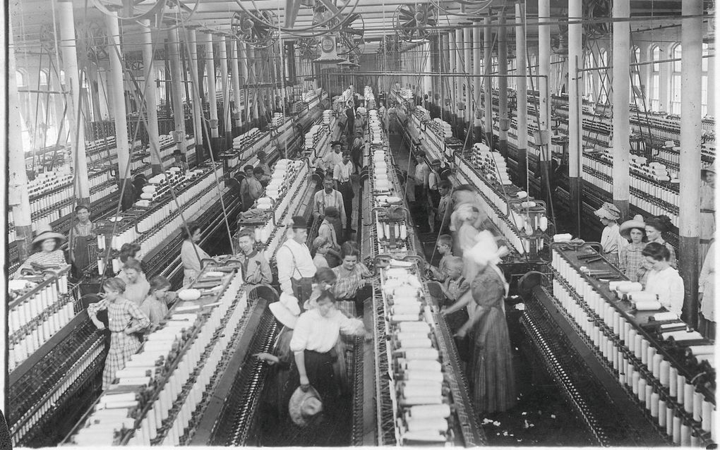 Zwart-witfoto van een fabriekshal waarin mensen werken bij spinmachines.