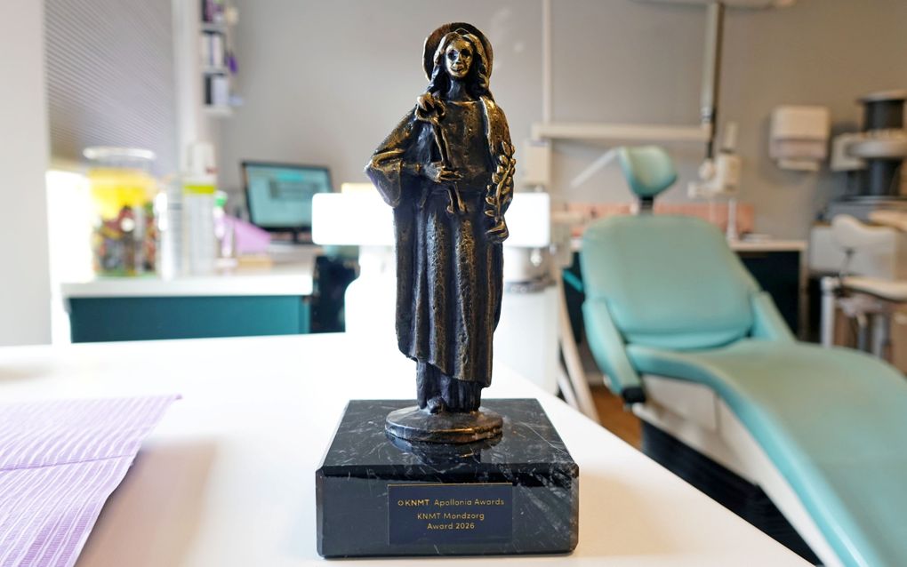 Een grijsbruin bronzen beeldje van een vrouw staat op een tafel in een tandartspraktijk.