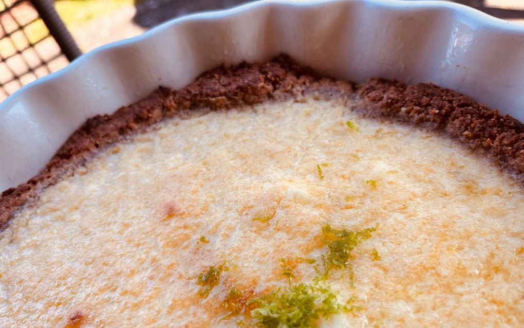 Gele taart in een taartschaal met groene rasp erop. 