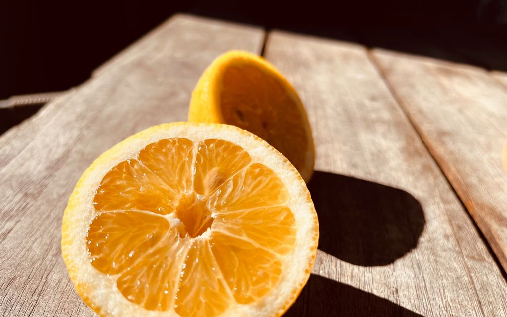 Een citroen die door de helft is gesneden ligt op een houten tafel. 