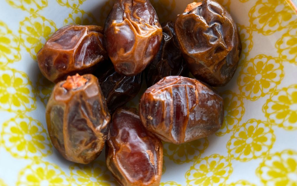Bruine dadels in een schaaltje met een geel bloemenmotief.