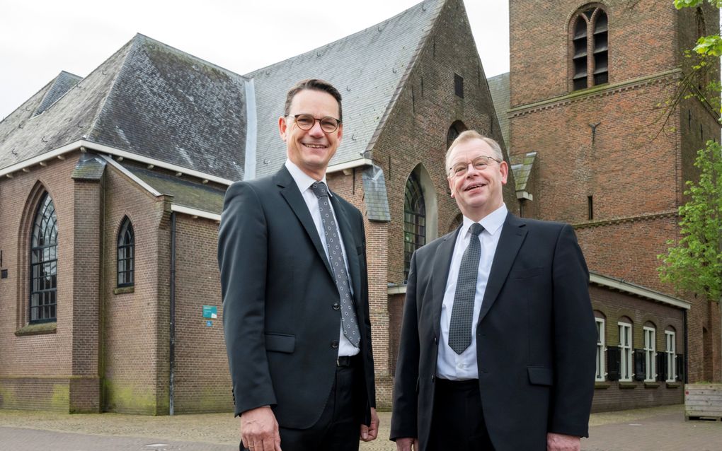 De hervormde ds. A.L. van Zwet (r.) en de hersteld hervormde ds. P.C. Hoek bij de Oude Kerk in Putten. beeld Ruben Schipper Fotografie