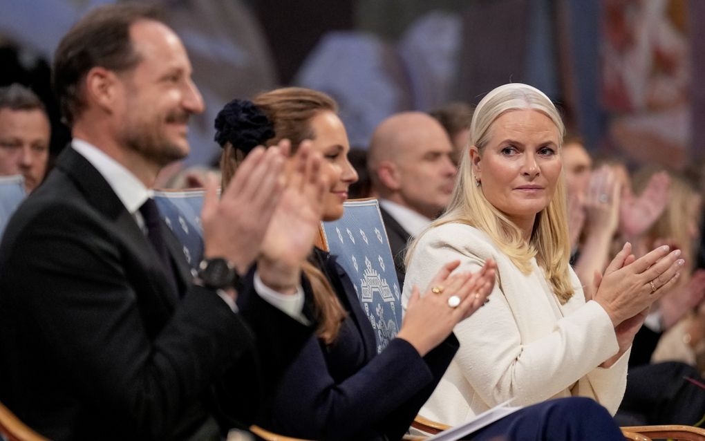 Mensen zitten op een rij en applaudisseren.