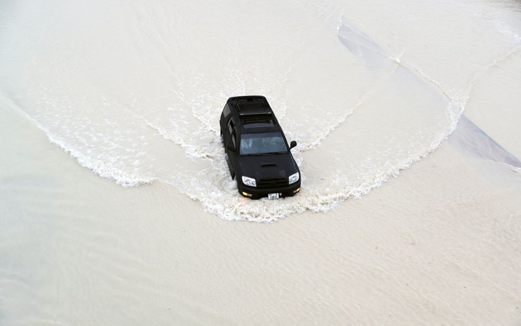 Een autobestuurder rijdt door grote plassen in Dubai. De staat werd getroffen door hevige regenbuien en onweer. beeld EPA, Ali Haider