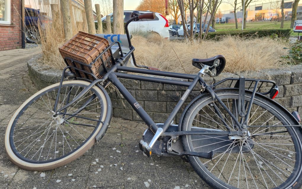Een fiets met een krat en een RD-fietstas voorop ligt op een muurtje.