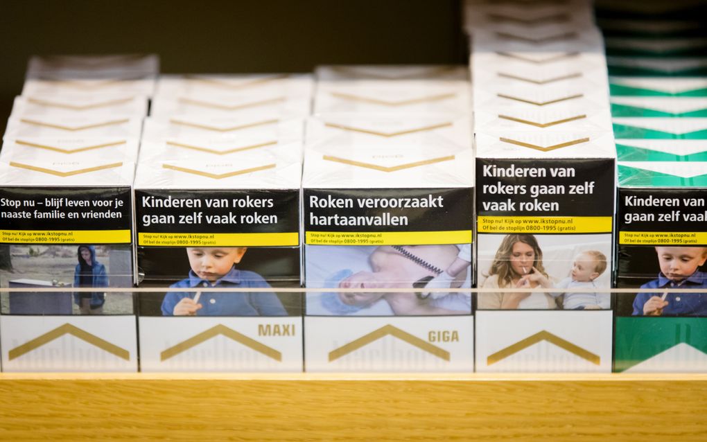 Pakjes sigaretten in een schap. Op de pakjes staan waarschuwende teksten, zoals: Roken veroorzaakt hartaanvallen.