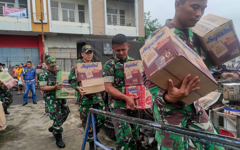 Indonesische militairen laden voedsel op een schip tijdens de evacuatie.  Beeld AFP, Ronny Adolof. 