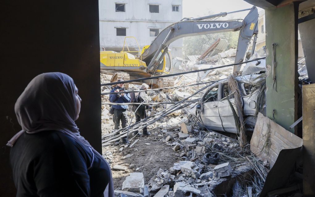 Een Libanese vrouw kijkt toe hoe er puin wordt geruimd na een Israëlische luchtaanval op Beirut.
