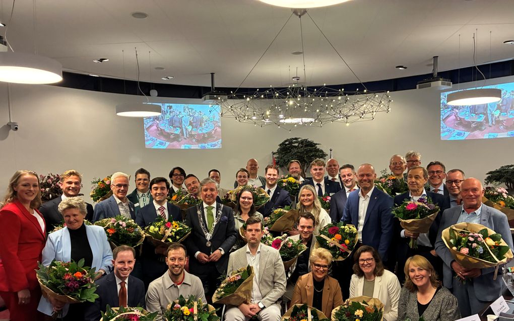 Groep mensen, netjes gekleed, met grote bossen bloemen.