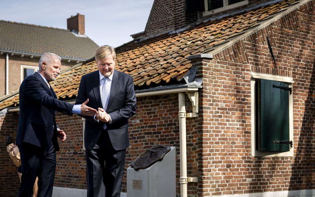 Twee mannen in een donker pak bij een zegel op een sokkel.
