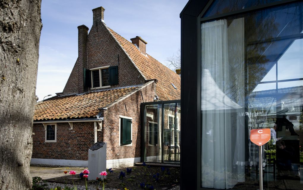 Een oud huis, met ertegenaan een glazen aanbouw.