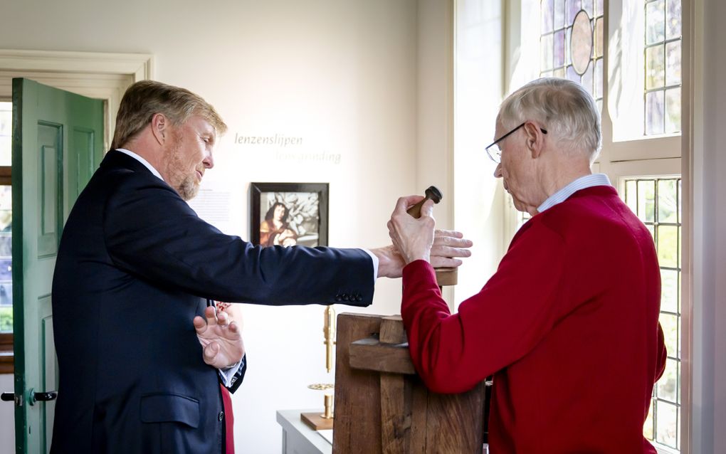 De koning voelt aan een houten object.