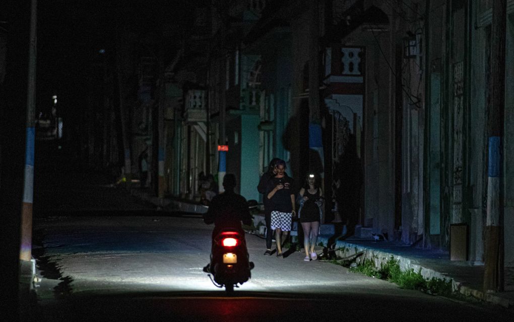 Een motor rijdt in een donkere straat. In het licht van de koplamp zijn drie mensen te zien.