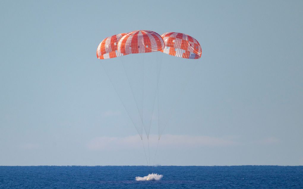 Drie rood-witte parachutes boven een kalme zee