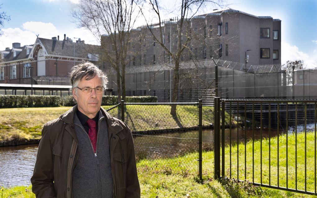 Dominee Van Gelderop, een man met grijs haar, bril op, voor een hek.