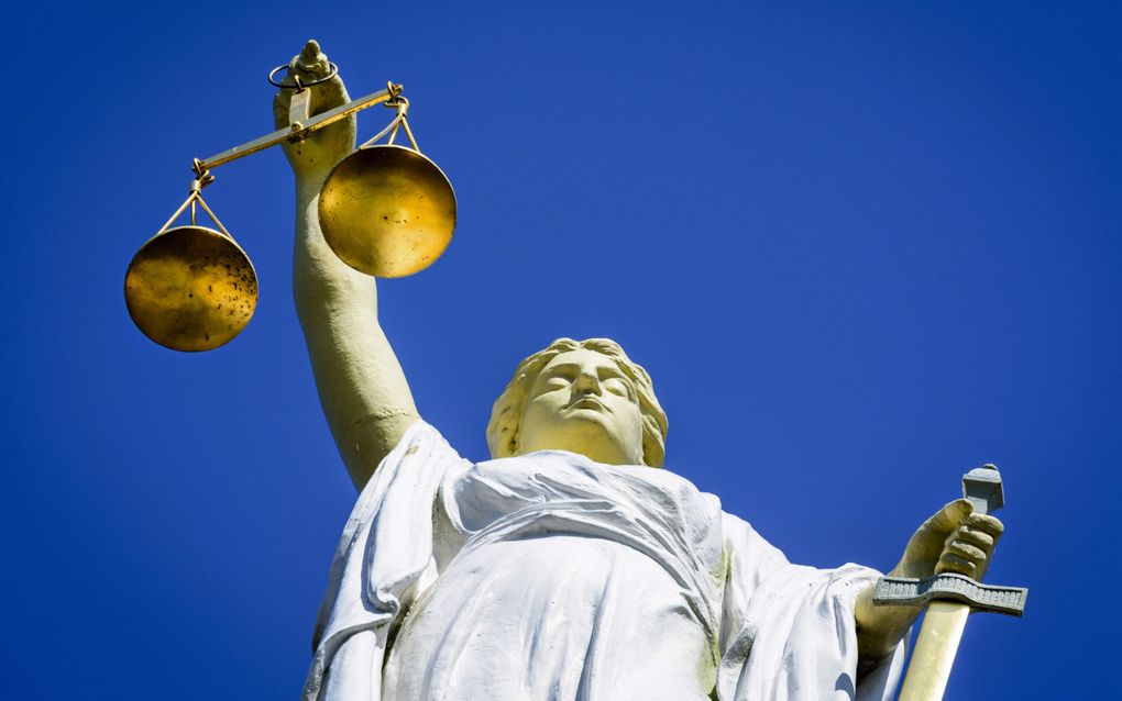 Wit beeld van Vrouw Justitia tegen blauwe lucht.
