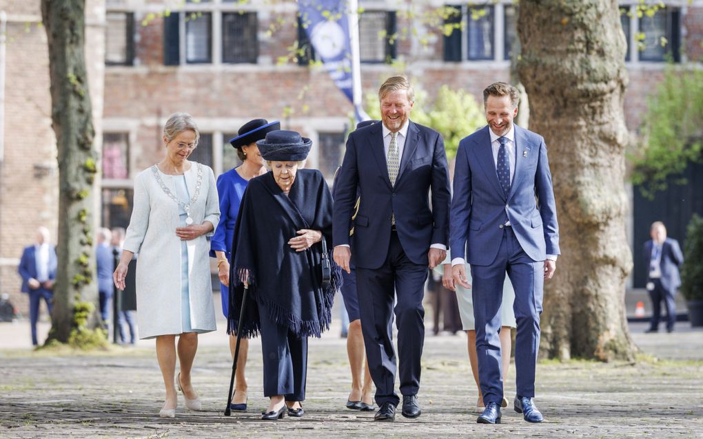 Een vrouw met een stok en enkele lachende mannen.