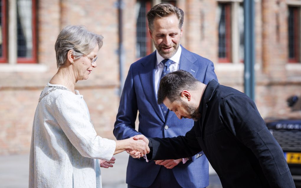 Een man buigt terwijl hij een vrouw een hand geeft.
