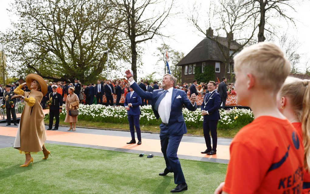 De koning en de koningin proberen balletjes uit de lucht te slaan. Ze hebben een soort rode handschoen aan.