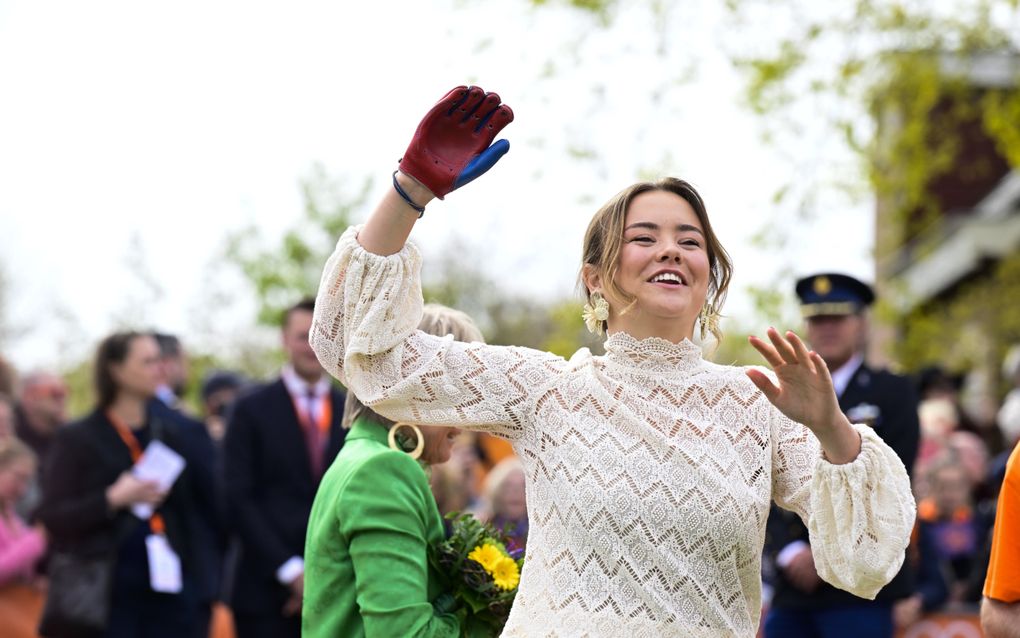 Prinses Ariane steekt een hand omhoog, terwijl ze lacht. Aan haar hand zit een rode leren handschoen.