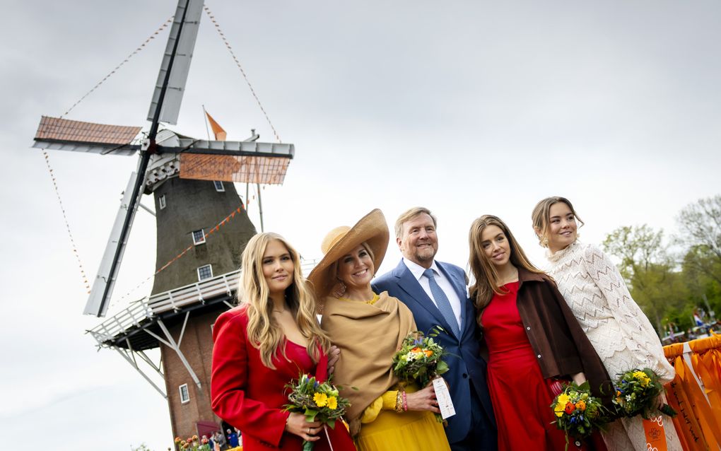 Van links naar rechts: prinses Amalia, de koningin, de koning, prinses Alexia en prinses Ariane. De vrouwen hebben een boeketje vast, met onder andere gele, rode en blauwe bloemen. Op de achtergrond een oude windmolen.