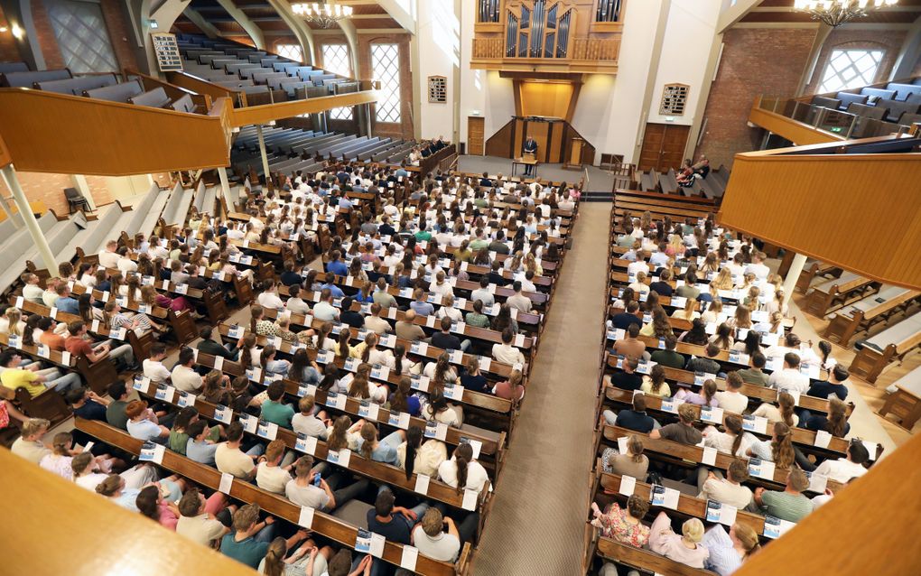Een kerkzaal vol mensen, van bovenaf gezien.