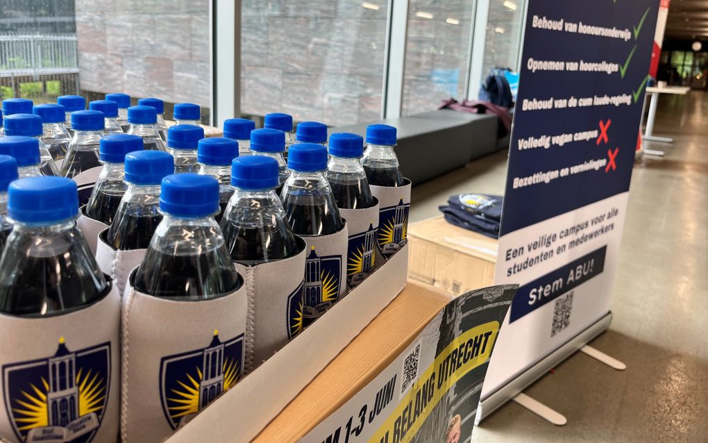 Flesjes water staan met een grijze hoes en een blauwe dop staan uitgestald op een tafel. 