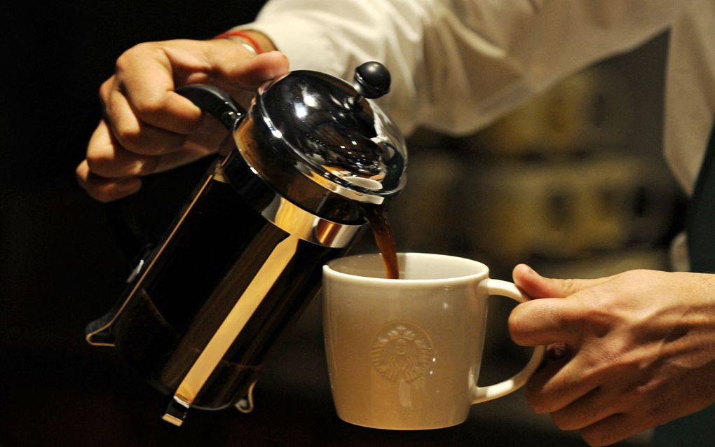 Een man in een wit overhemd schenkt koffie in een beker.