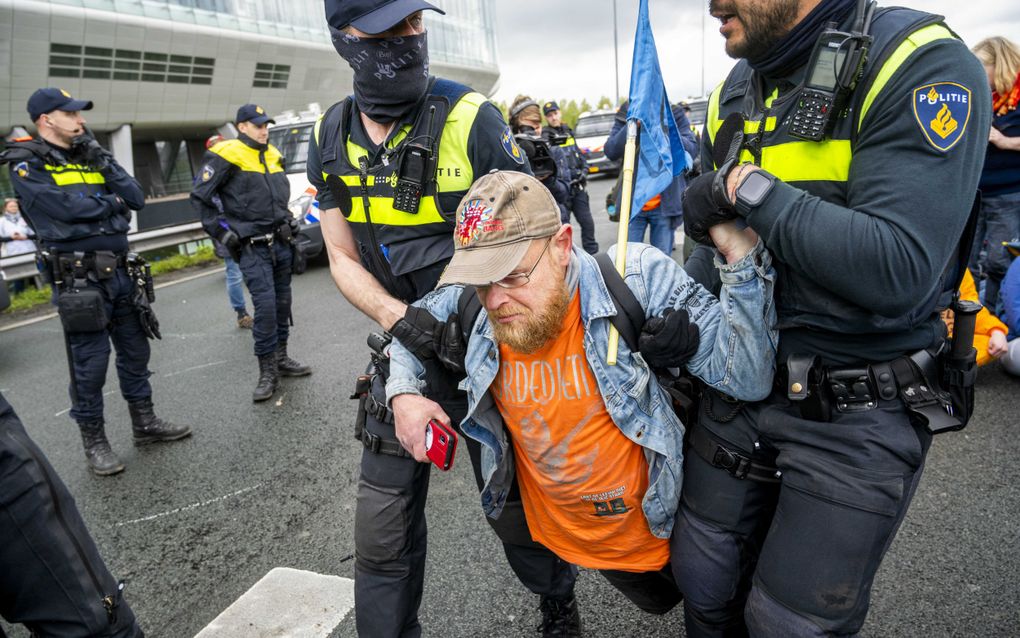 Een demonstrant van Extinction Rebellion wordt afgevoerd tijdens een blokkade van de snelweg A10 ter hoogte van het voormalig ING-hoofdkantoor op de Zuidas. Beeld ANP, Evert Elzinga